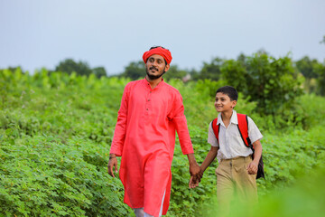 Young indian farmer telling some information to his child in green field