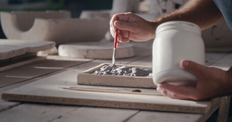 Crop artisan smearing paint on ornament