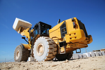 A big loader holding huge marble block. Loader machinery working on marble quarry with cloudy sky