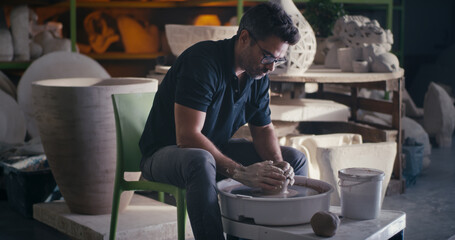 Fototapeta na wymiar Focused potter making vase on wheel