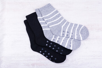 Pair of black and gray woolen socks on white wooden background