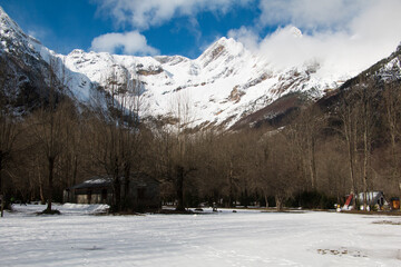 Snowy landscape in pyrenees. Mountains with snow and trees without leaves