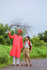 Young indian farmer telling some information to his child in green field