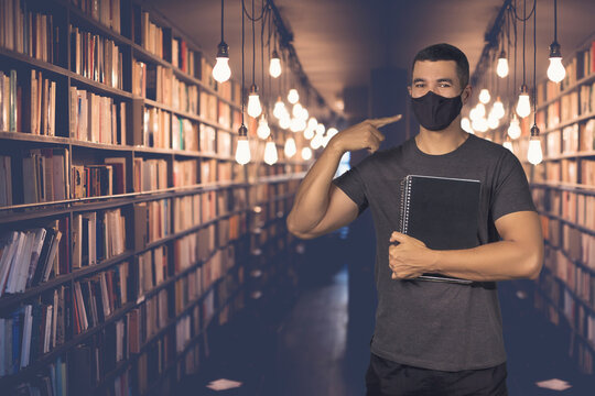 A Studant Man With Covid 19 Coronavirus Mask Holding A Copybook In The Library