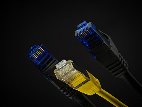 Stecker von Netzwerkkabel (Patchkabel/Cat5) in blau und gelb vor dunklem Hintergrund