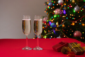 New Year's photo glasses on a red table with champagne on the background of the Christmas tree with lights and sides. Holiday and bull year