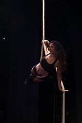 Young woman doing acrobatics on a black background