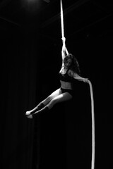 Young woman doing acrobatics on a black background