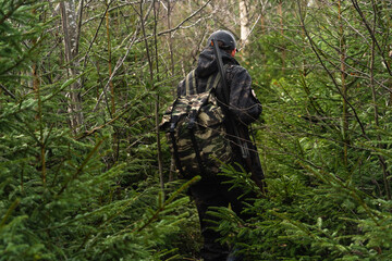 Hunter with a gun and a backpack in the forest	