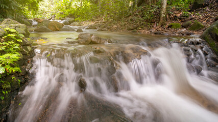 Beautiful small waterfall in deep rainforest wild with water motion.