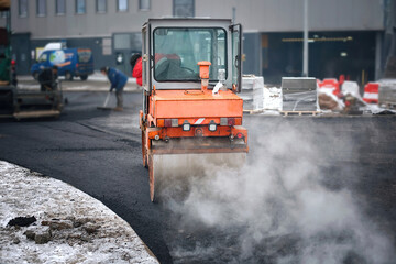 Vibration roller compactor lay new asphalt surface in wintertime. Road construction, asphalt roller...