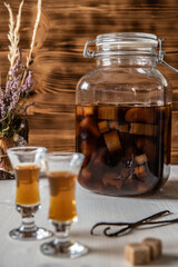 Likör aus Rhabarber, Vanille, Kandiszucker und Schnaps auf weißem Tisch mit braunem Hintergrund