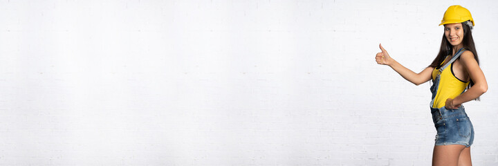 A construction worker shows with her thumb that everything is fine. Positive signs and symbols...