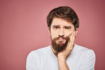 Obraz premium Emotional bearded man in white T-shirt discontent pink background