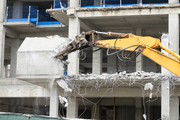 Excavator machine with hydraulic crashers at demolition of the house. House being demolished by special machinery.