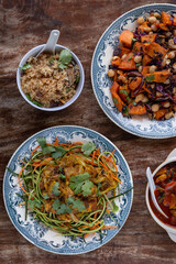 
full table healthy Indian, Asian and Mediterranean dishes with white beans, lentils, sweet potatoes, rice and vegetables