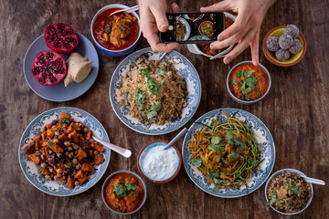 Cellphone taking picture of a table full of healthy and colorful asian and Mediterranean food