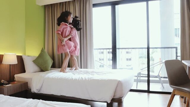 Happy family two daughters ่jumping on bed