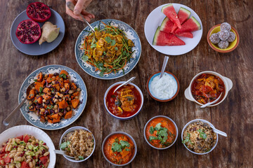 table full of healthy and colorful  food with detail of hands touching asian and Mediterranean food