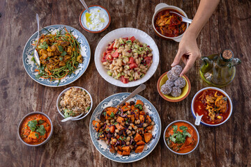 table full of healthy and colorful  food with detail of hands touching asian and Mediterranean food
