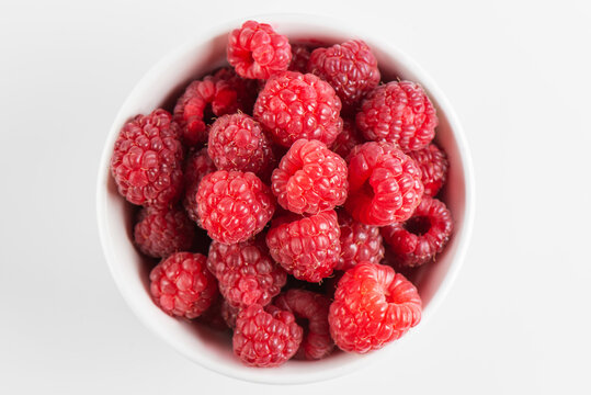 Fresh raspberries in a bowl isolated on white background, top view