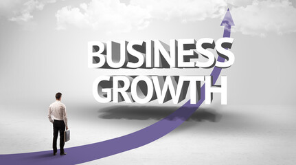 Rear view of a businessman standing in front of BUSINESS GROWTH inscription, successful business concept