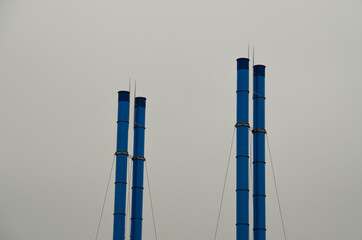 Blue factory chimneys against a gray sky. Industrial landscape.