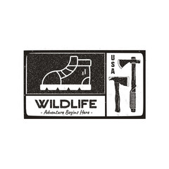 Hand drawn travel badge with hiking boot, axes and quote - Wildlife adventure begins here. Camping emblem patch in retro style. Stock wanderlust label isolated. Monochrome stamp