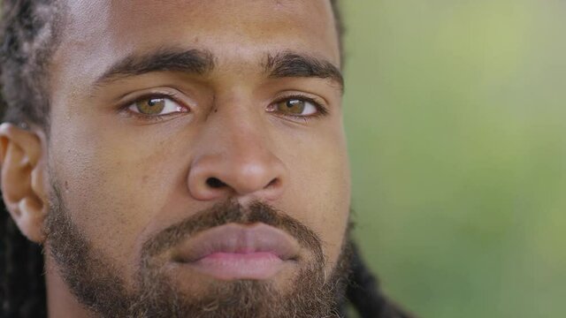 Portrait of attractive black man looking to camera and smiling, in slow motion