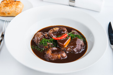 Veal ossobuco sprinkled with dill and garnished with chili on a white plate