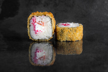 Tempura rolls with shrimp, tomato, cream cheese and tobiko caviar on a dark background with reflection