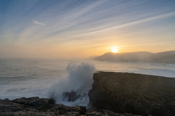 Obraz premium huge storm surge ocean waves crashing onto shore and cliffs at sunrise