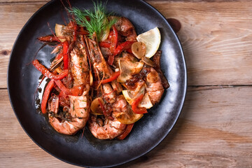 Delicious fried langoustines in sauce on a black plate, prepared in an Asian style. Fast and ready meal concept