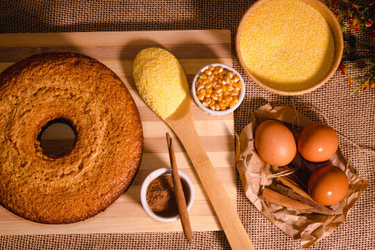 Brazilian corn cake made with a type of corn flour (Fuba) on the wood table and flour on the spoon and cinnamon. top view .generally typic in northeast of brazil. founded in traditional party .