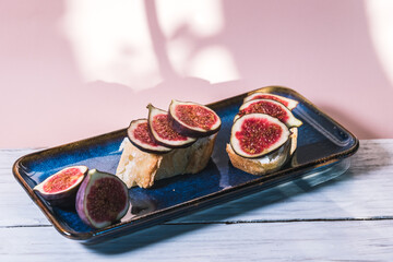 Bruschetta of baguette, cheese and figs are on a plate on the table. The concept of minimalism in...