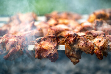 Shashlik or shish kebab preparing on barbecue grill over hot charcoal. Grilled pieces of pork meat on metal skewers.