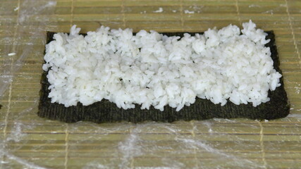 A woman presses rice on a nori leaf. Cooking sushi at home. Close-up shot