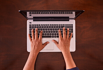 Manos de hombre escribiendo en teclado de laptop sobre escritorio