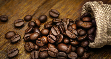 Coffee bean in sackcloth bag on wooden table.
	