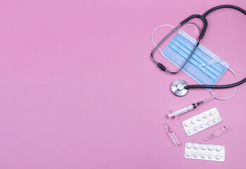 stethoscope, face mask, pills, syringe, ampoules, on a pink background.