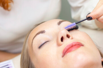 Eyelash extension procedure. Beautiful woman with long eyelashes in a beauty salon. Eyelashes close up. brush in the hands