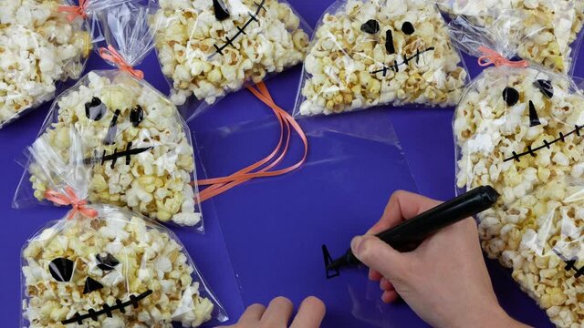 Preparing Halloween gifts, Woman's hands creating Halloween packaging for popcorn, Presents in the form of skull