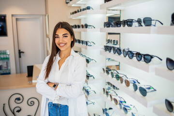 Optician selling glasses at the optics. Happy optician selling glasses and looking at the camera smiling. Friendly eye doctor selling glasses at an optician's shop and looking at the camera smiling
