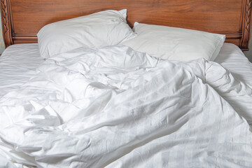 unmade bed with white linens. Unmade empty bed. Close up of white sheets on bed