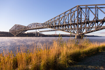 Beautiful early morning view of the 1919 steel Quebec Bridge over the St. Lawrence river seen from the Samuel-de-Champlain Walk on the north shore, Quebec City, Quebec, Canada - obrazy, fototapety, plakaty