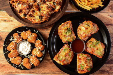 Assorted foods cheesy garlic bread,tandoori chicken pizza,chicken nuggets and french fries