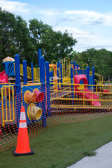 Empty children's playground blocked off by orange fence, closed due to coronavirus outbreak