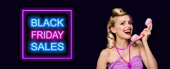Photo of young blond woman with phone tube, dressed in pinup style, over black background. Black Friday sales sign.