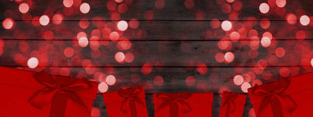 Festive celebration / Christmas / Silvester / holiday / Birthday background banner template - Abstract red sparkles bokeh lights and red gift boxes on rustic black wooden boards wall / wood texture