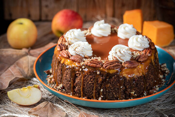 Pumpkin cheesecake. Curd cake with caramel, nuts, whipped cream, pumpkin, apples and autumn leaves on the background.